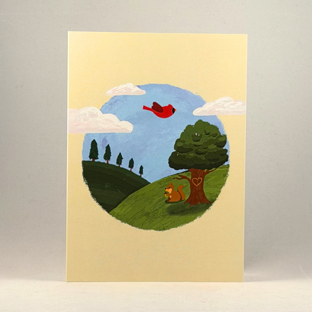 A 5x7 cream-colored greeting card featuring a hand-painted style illustration of a pastoral landscape. The scene shows a blue sky with white clouds, a red bird flying, a green hill, a tree with a heart on the trunk, and a small squirrel.