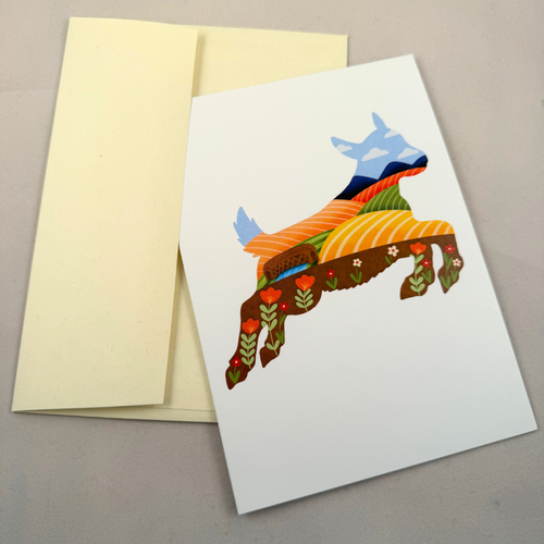 A white greeting card featuring a colorful stylized goat silhouette made of layered patterned shapes, shown with a pale yellow envelope on a neutral gray background.