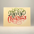 A 5x7 greeting card with a cream-colored background featuring the words 'Merry Christmas' in decorative script. 'Merry' is written in dark green with a gradient effect, and 'Christmas' is written in red with a matching gradient.