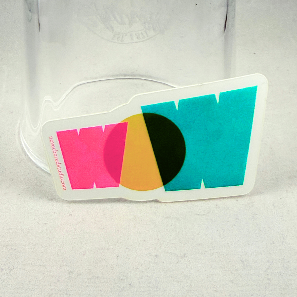 A die-cut sticker eaturing a colorful geometric design with overlapping pink, yellow, green, and teal letters spelling out 'WOW' on a white border, placed in front of a clear glass jar on a light gray surface.